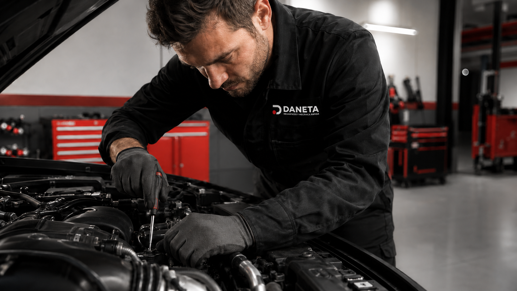 Mecánico de Automóviles Daneta realizando el mantenimiento del motor de un vehículo en un taller profesional.